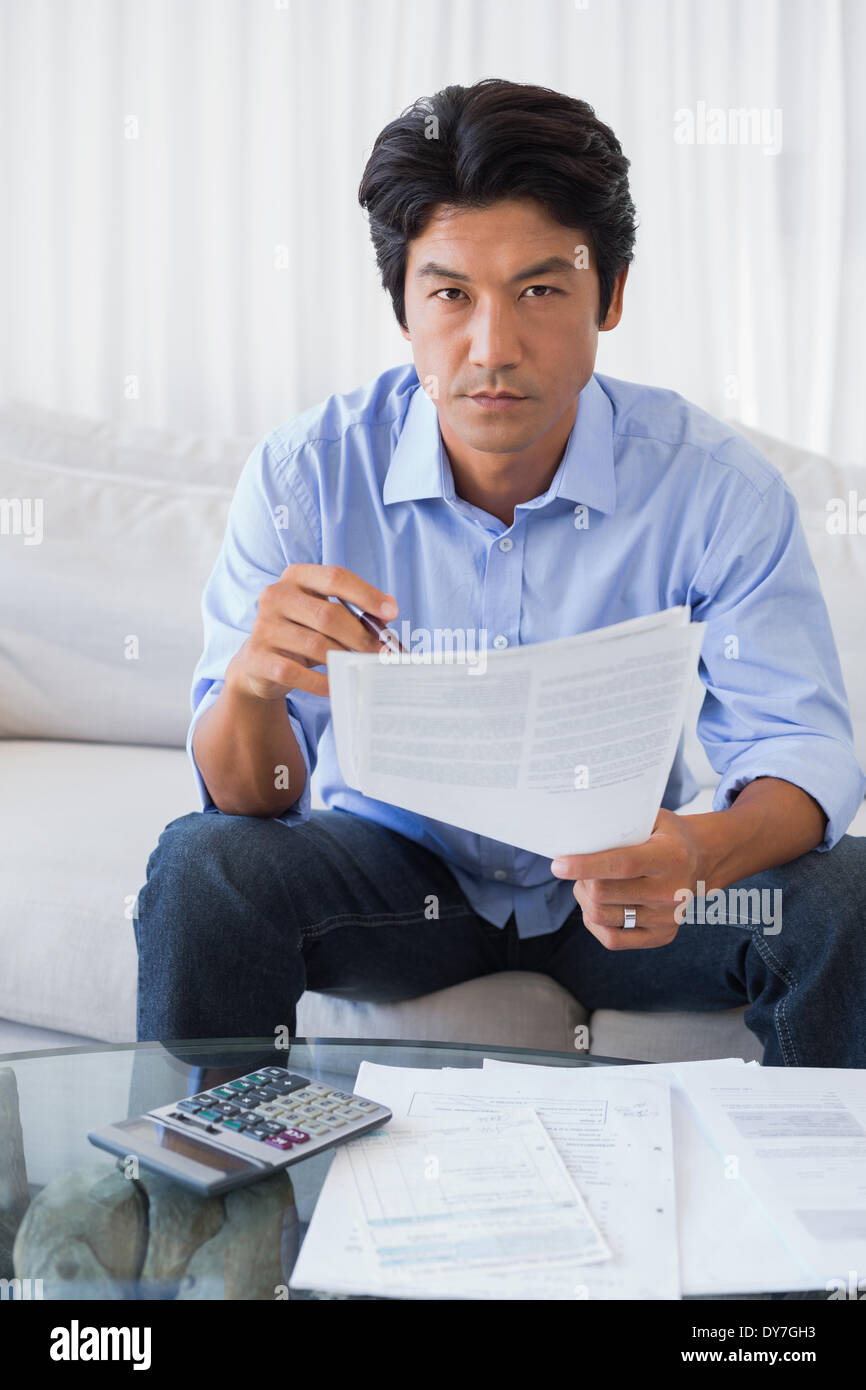 Man sitting on couch working out his finances Stock Photo