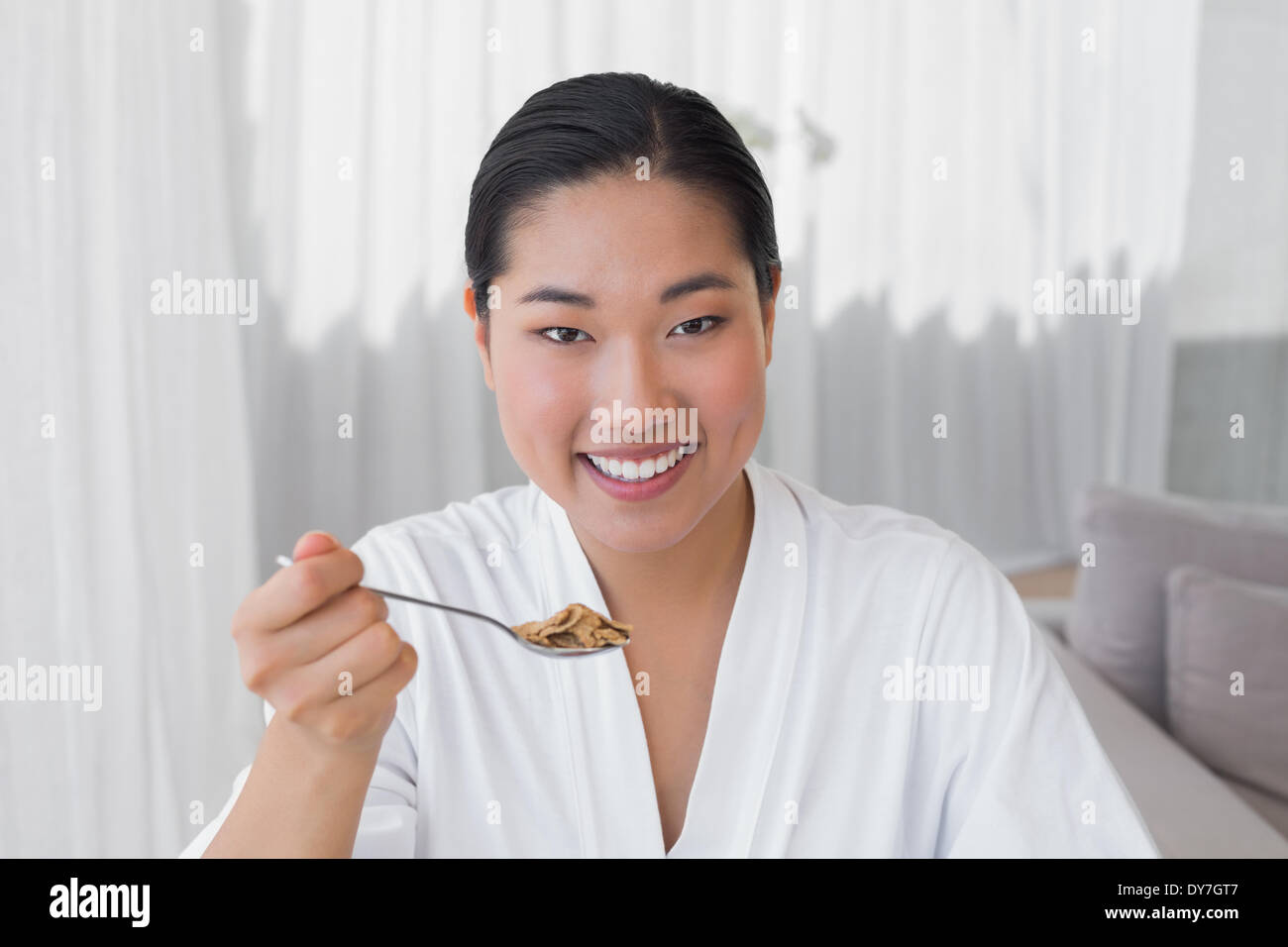 Happy woman in bathrobe having her breakfast Stock Photo