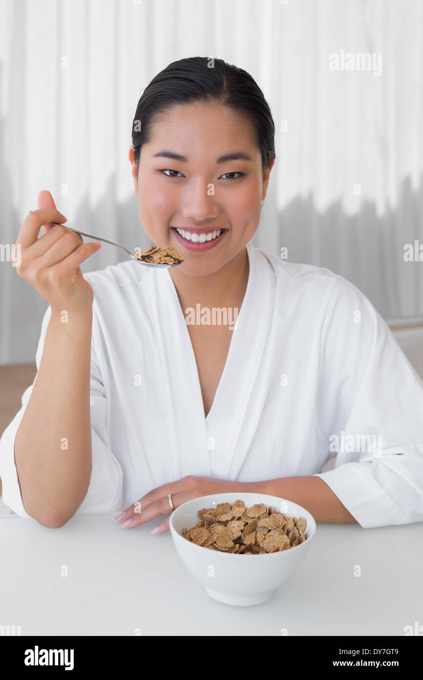 Happy woman in bathrobe having her breakfast Stock Photo