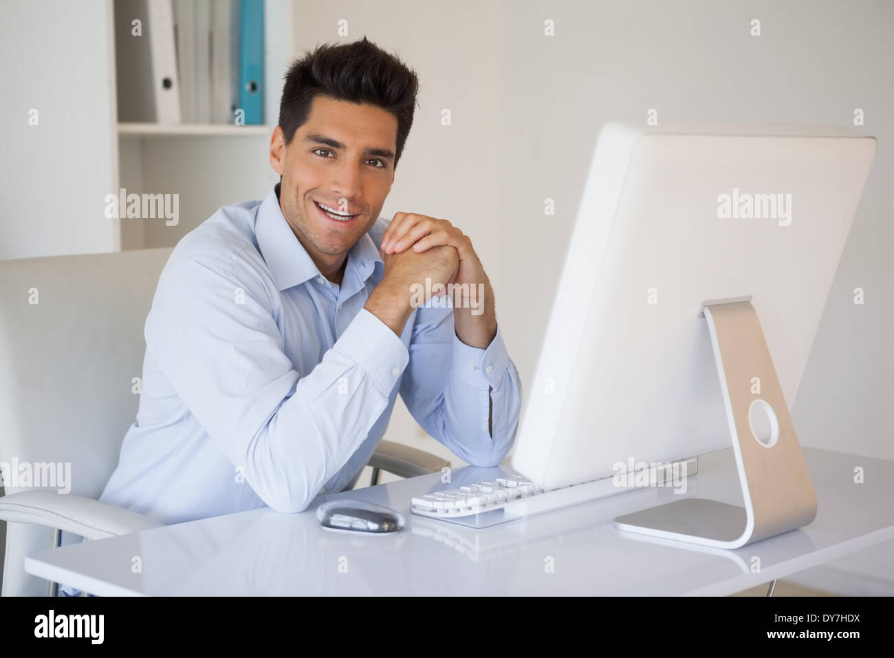 Casual businessman smiling at camera at his desk in his office Stock ...