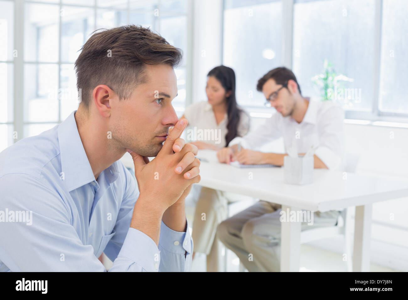 Casual businessman thinking with team behind him Stock Photo - Alamy