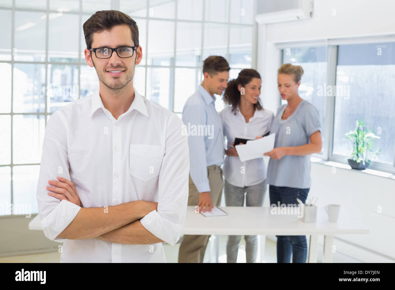 Casual businessman smiling at camera with team behind him Stock Photo ...