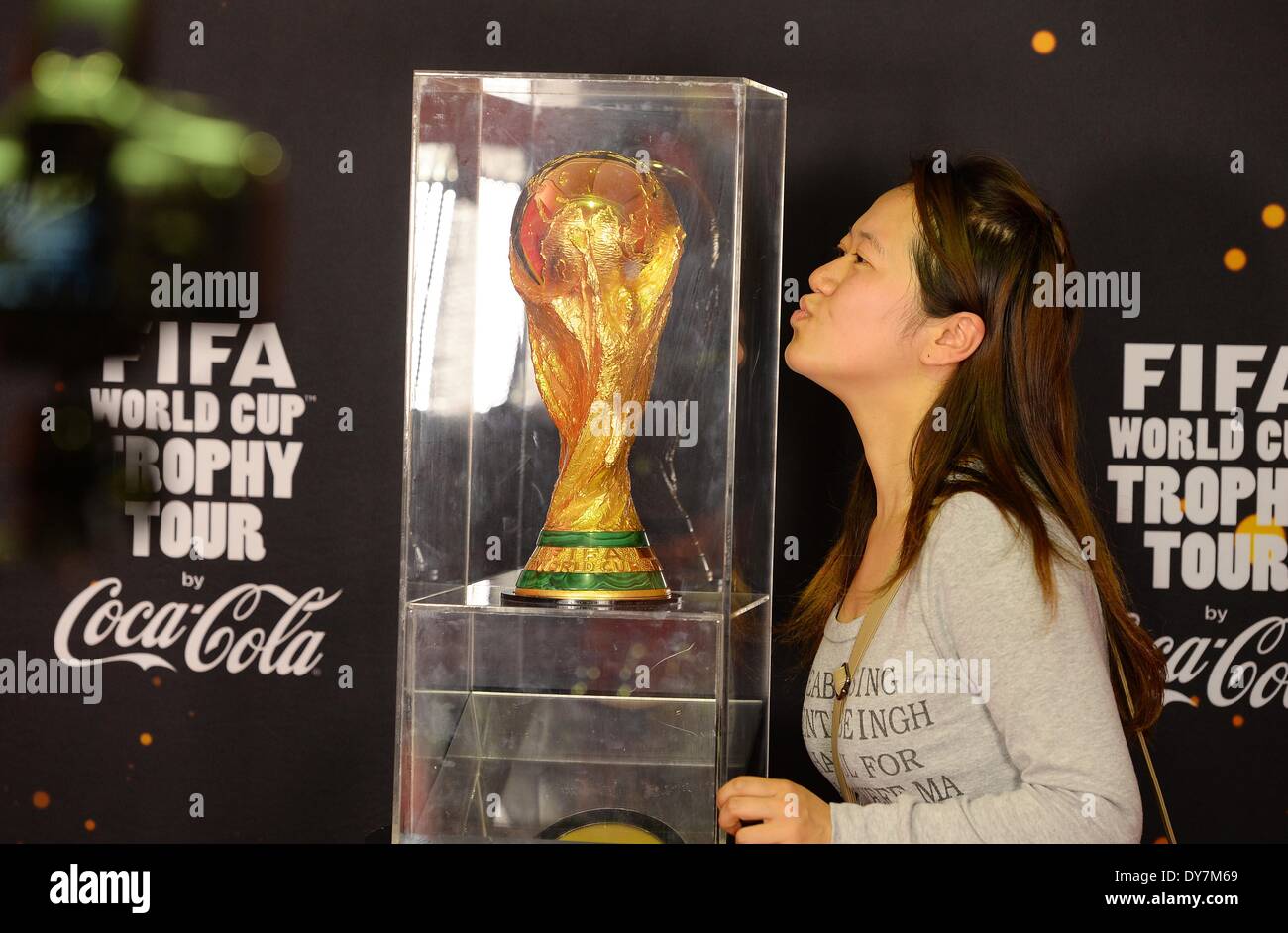 Shanghai. 9th Apr, 2014. A woman poses for a photo with the FIFA World Cup trophy on display in Shanghai, east China, April 9, 2014, as part of its world tour ahead of the Brazil 2014 World Cup finals this summer. © Lai Xinlin/Xinhua/Alamy Live News Stock Photo