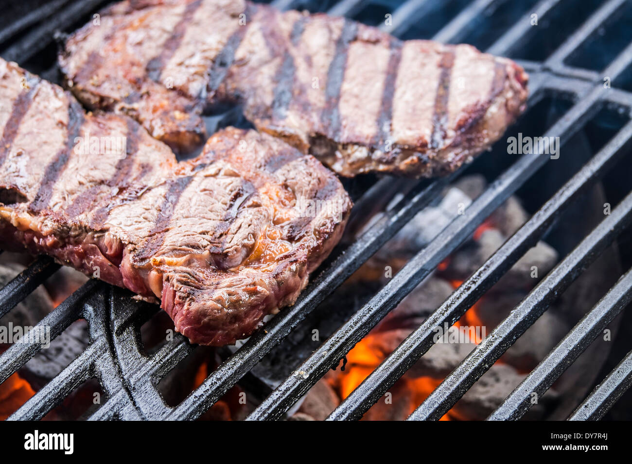 Beef steaks grilling over charcoal on barbecue grill Stock Photo Alamy