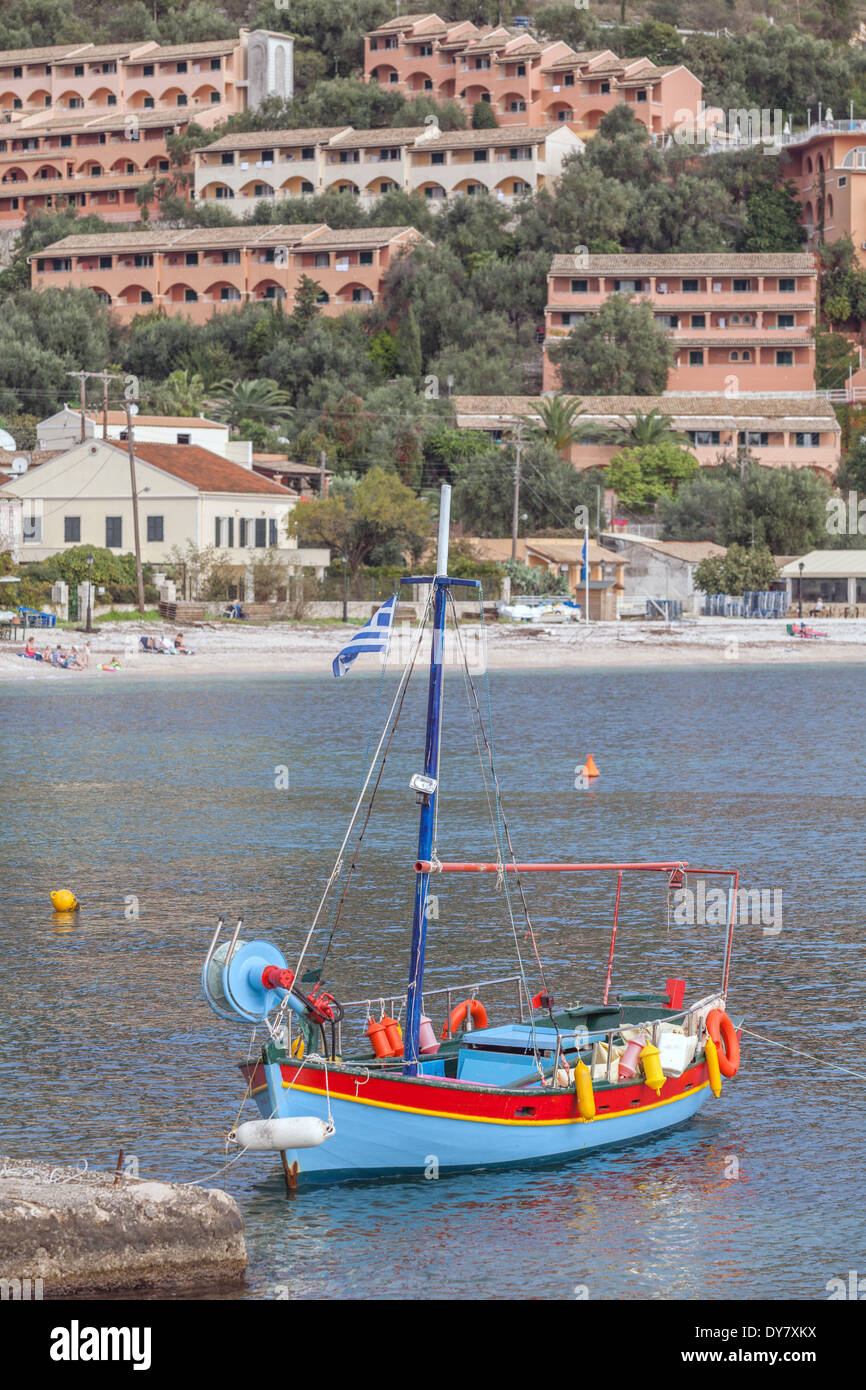 Kalami bay, Corfu, with new holiday villas on the cliff and a traditional fishing boat moored in the foreground (name removed). Stock Photo