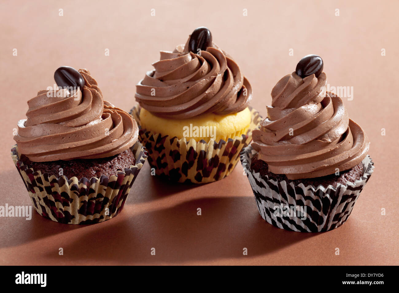 Three with mocha beans decorated cup cakes in paper cups in front of ...