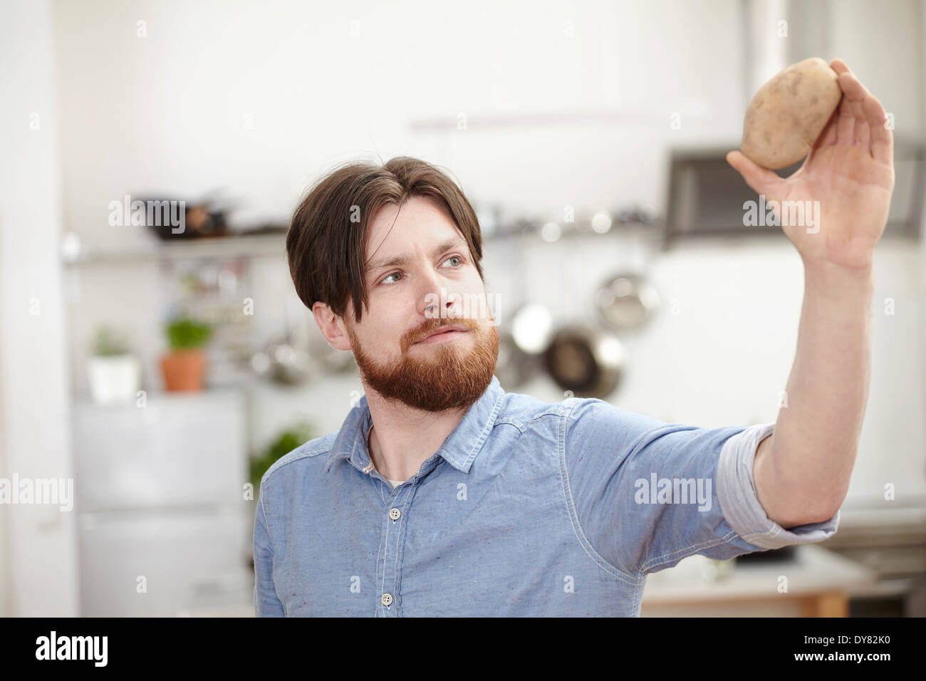 Man in kitchen holding potato Stock Photo - Alamy