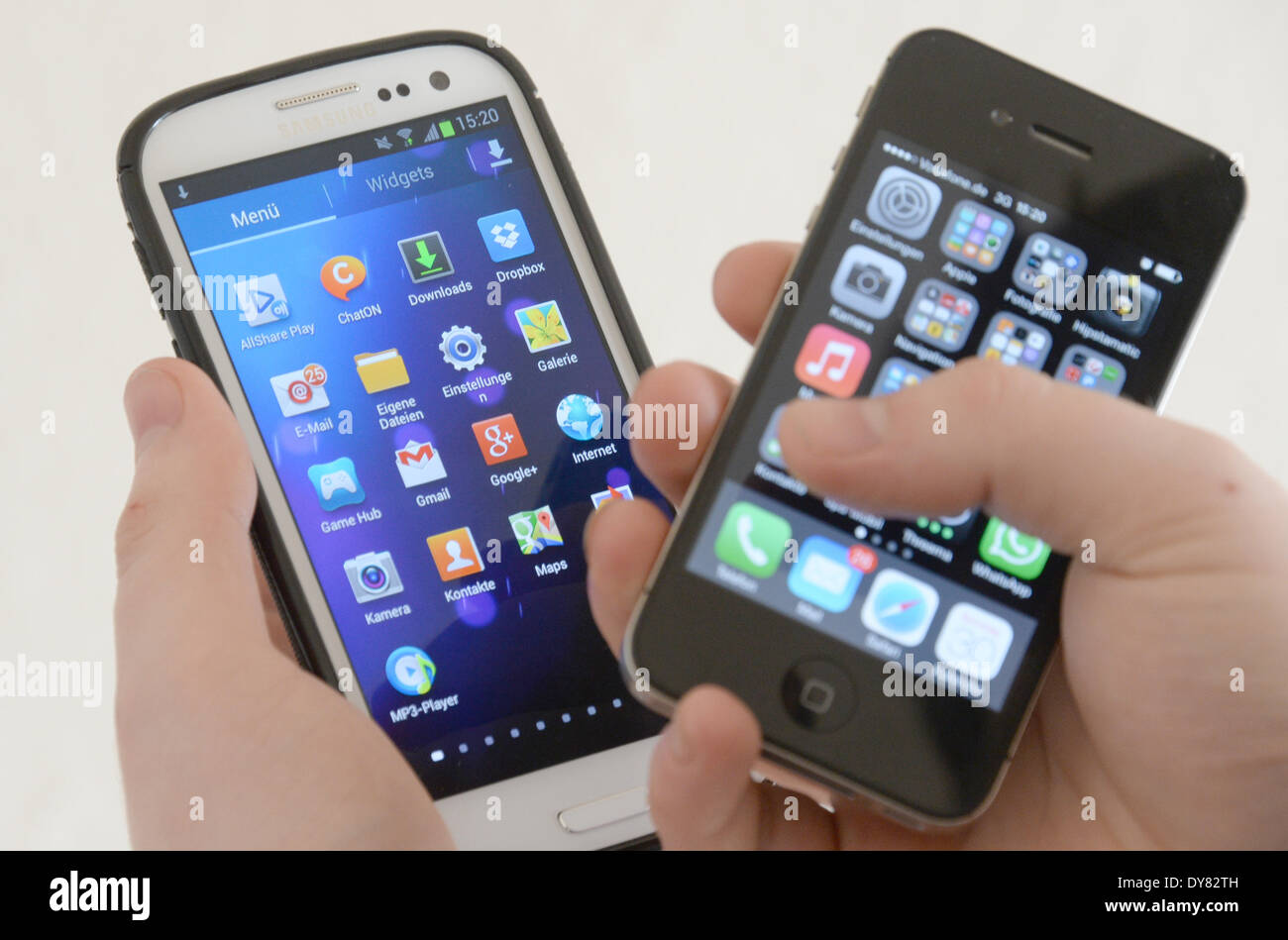 ILLUSTRATION - A man holds an Apple iphone 4s (R) and a Samsung Galaxy S3 in her hands in Hamburg, Germany 30 March 2014. The patent dispute between rivals Apple and Samsung is entering the second round with a trial that started in California, USA, on 31 March 2014. Photo: Marcus Brandt/dpa Stock Photo