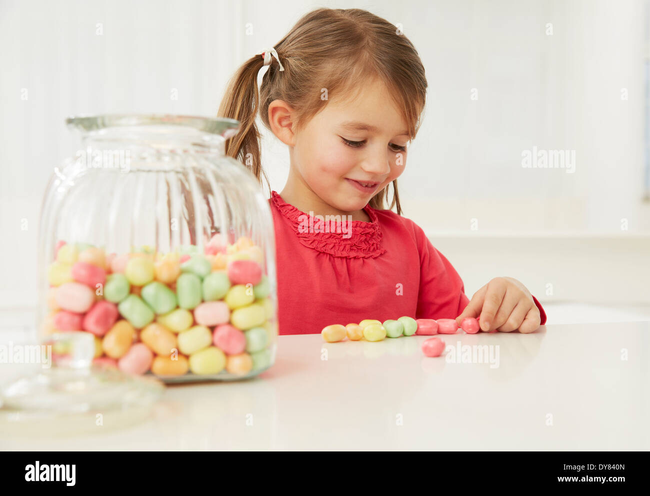 Germany, Munich, Girl with candy jar, counting candies Stock Photo Alamy