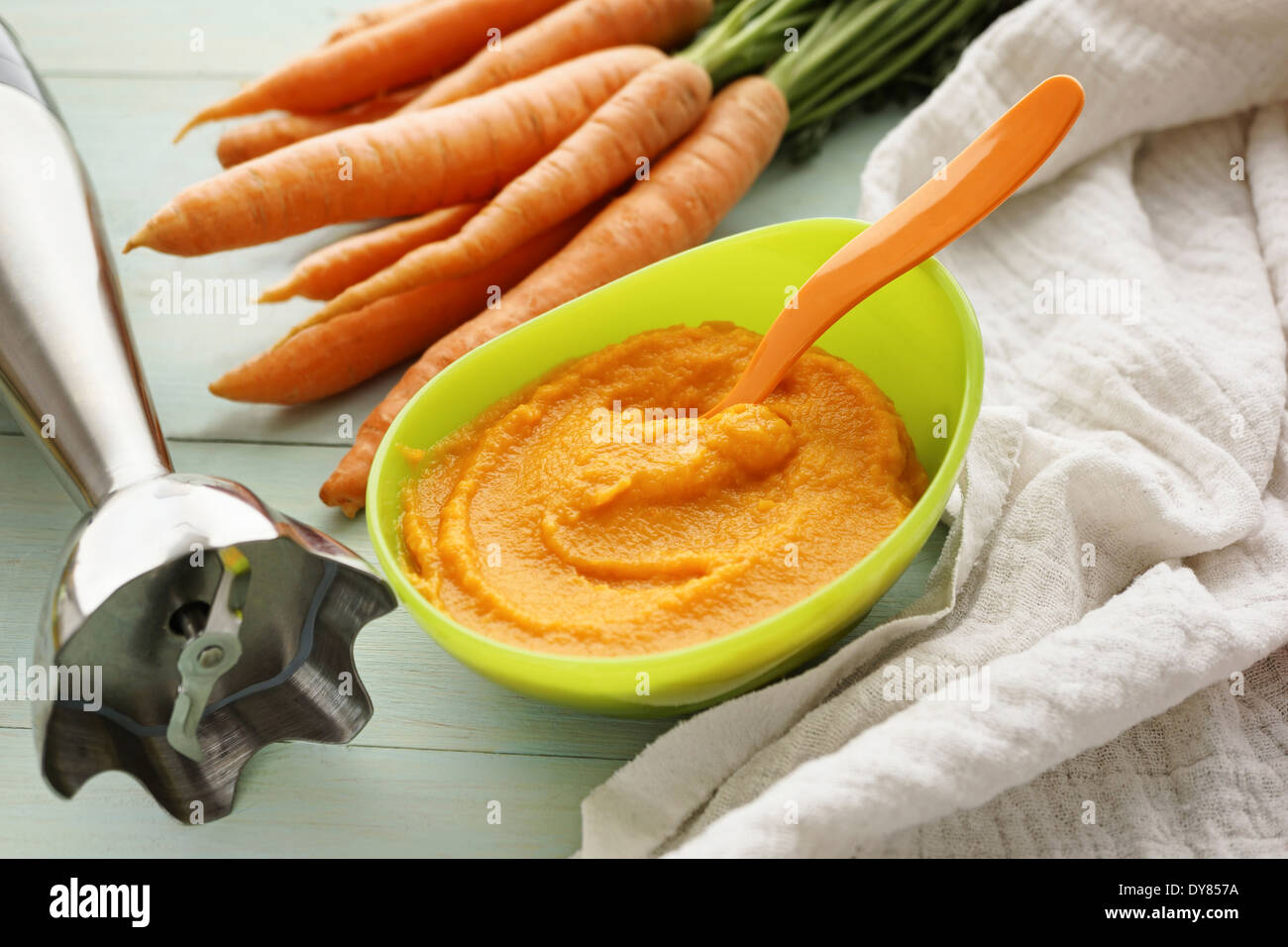 Immersion blender, bowl of carrot puree, carrots and cloth Stock Photo