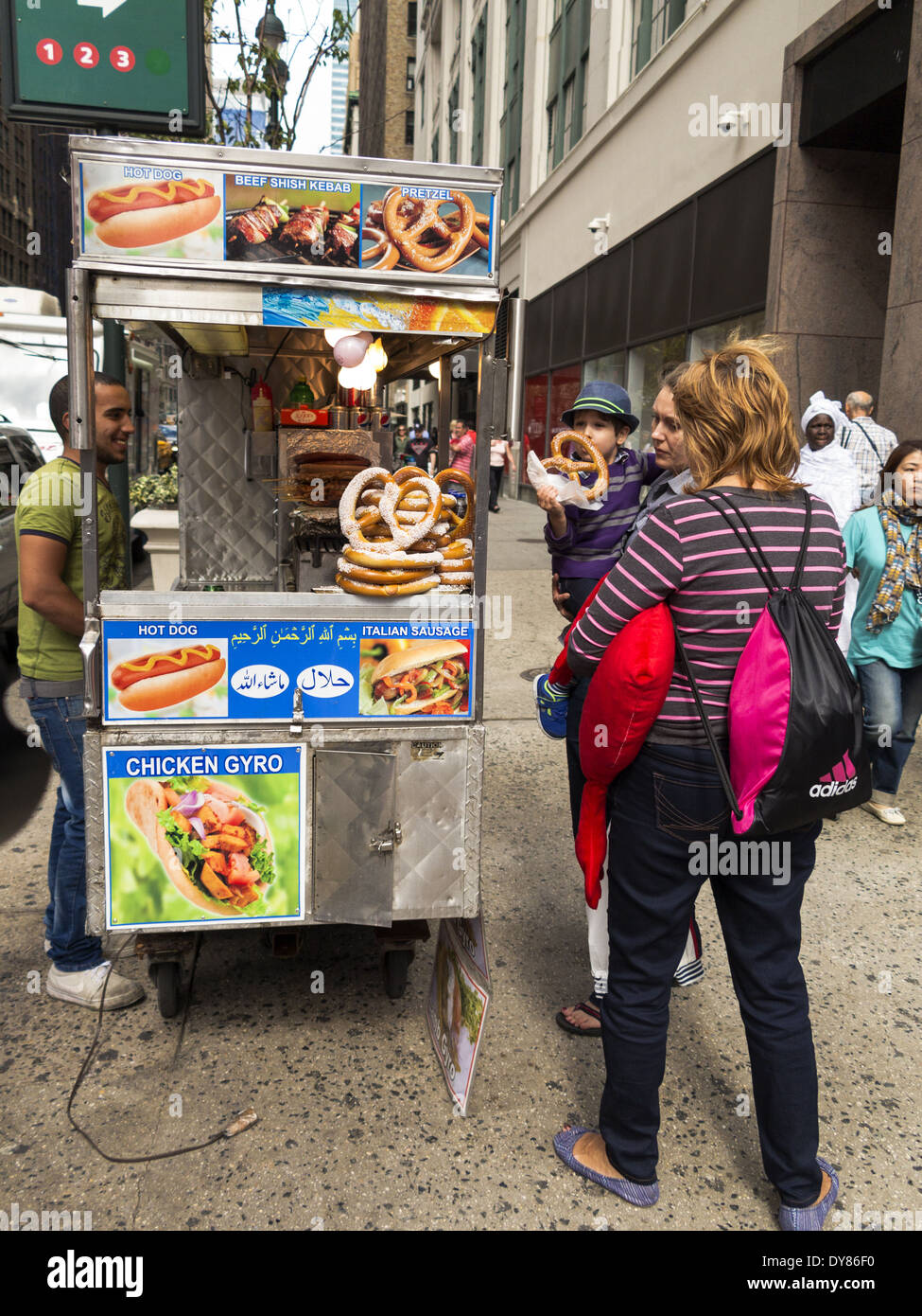 Buying pretzels at sidewalk hot dog cart street vendor New York USA Stock Photo