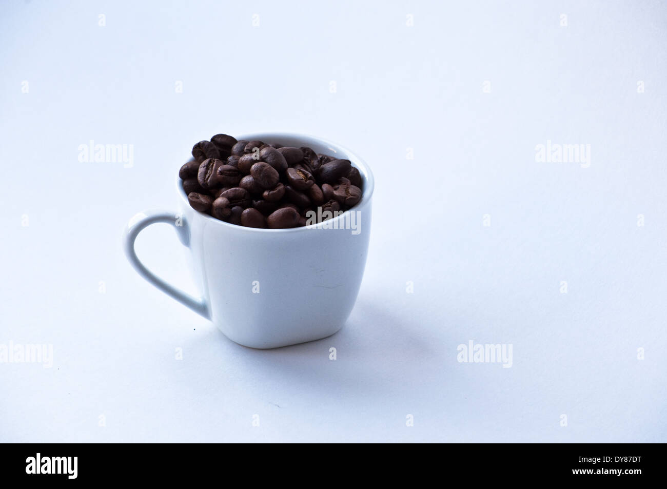 White coffee Cup, in which piled roasted coffee beans. Stock Photo