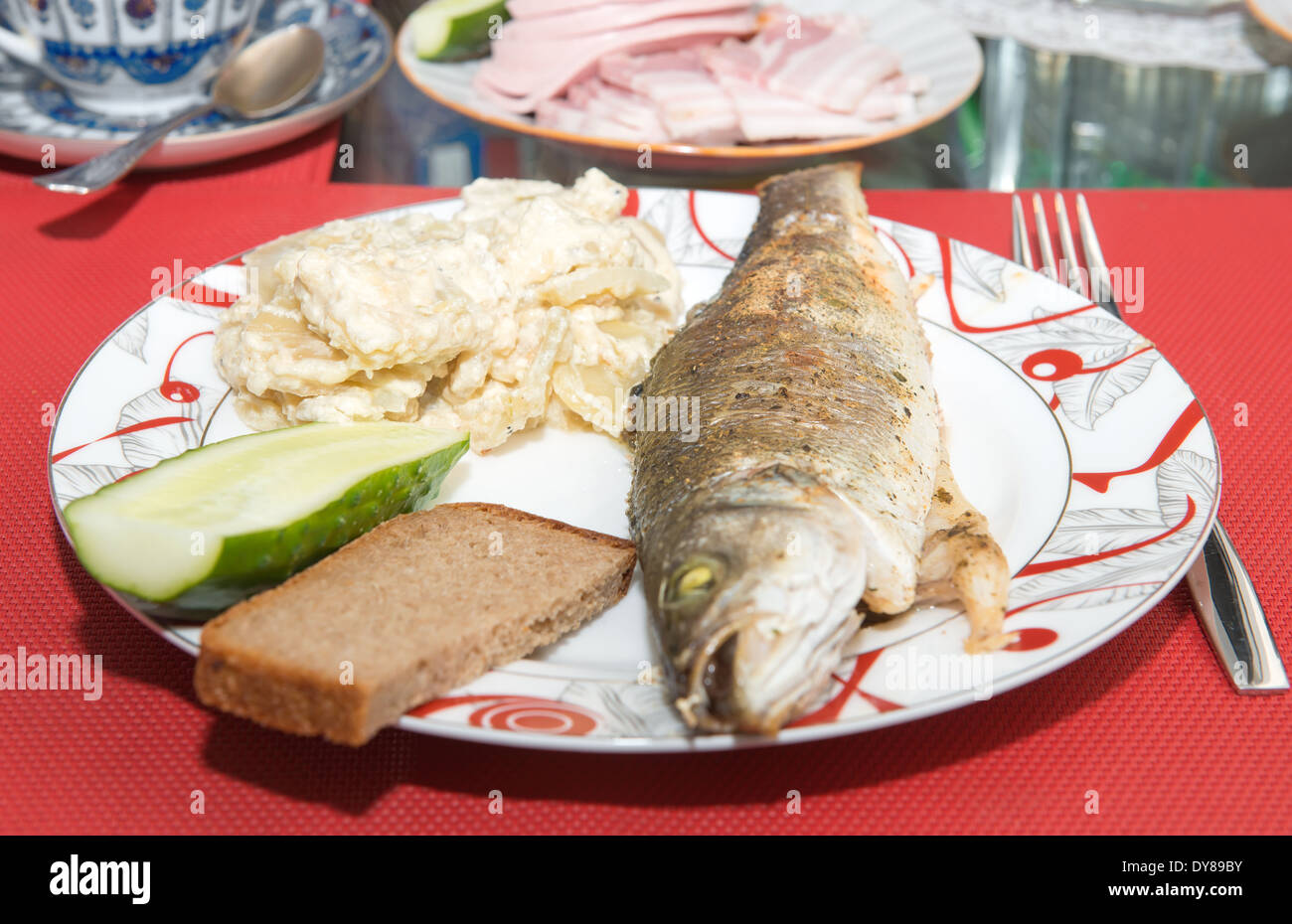Roasted fish sea bass with potatoes, bread and cucumber Stock Photo Alamy