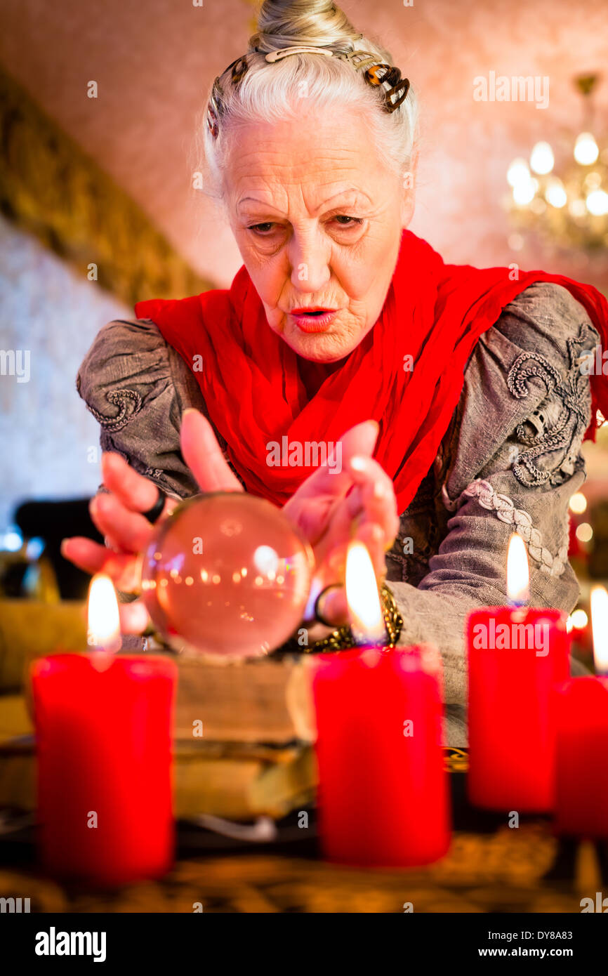 Female Fortuneteller or esoteric Oracle, sees in the future by looking into their crystal ball during a Seance Stock Photo