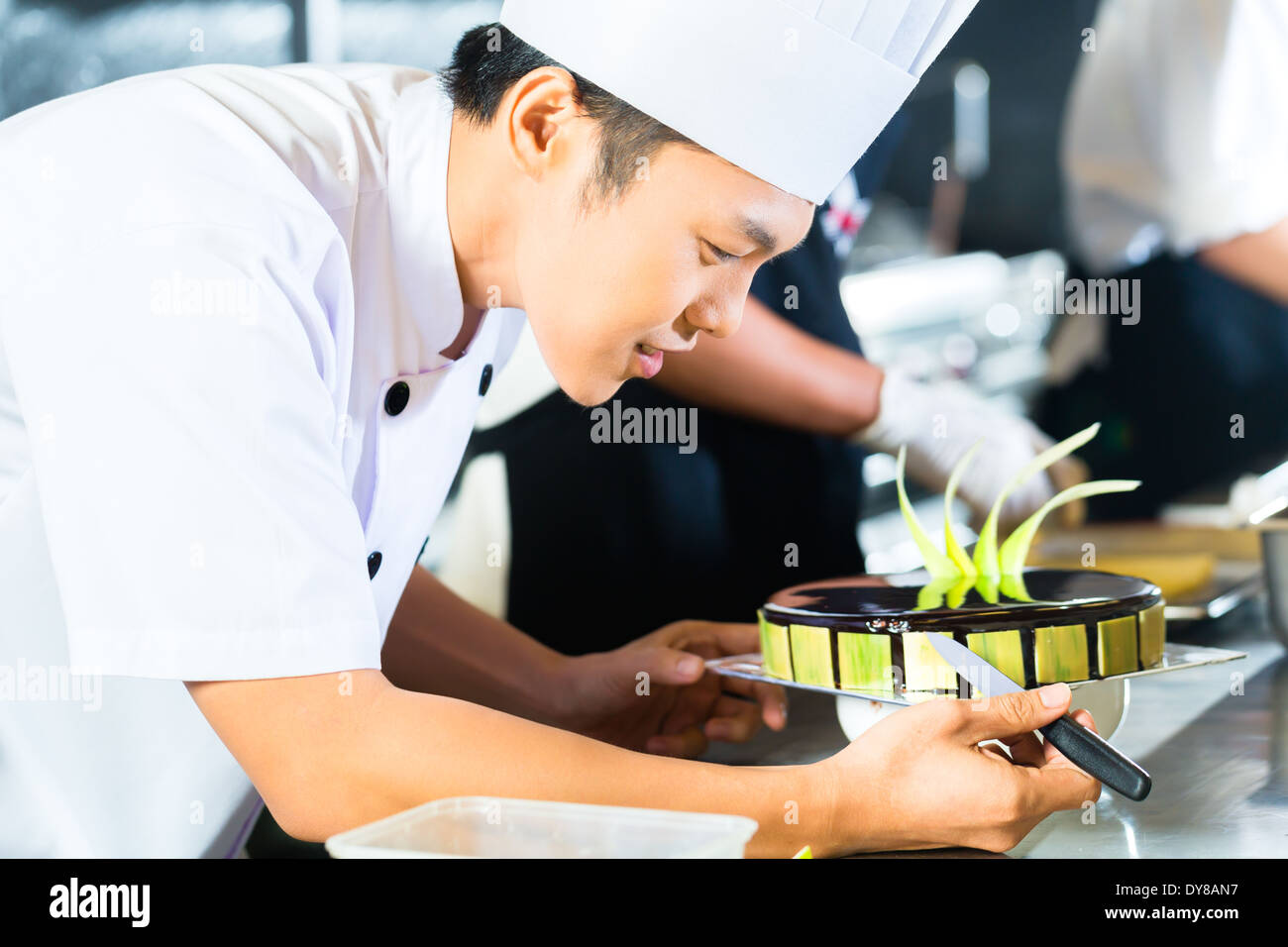 Side view of young chef decorating cake Stock Photo