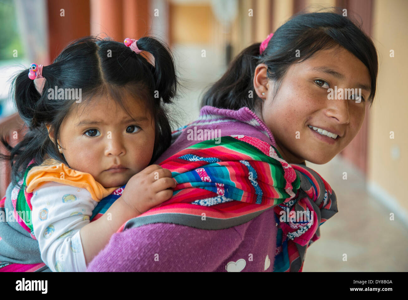 South America, Peru, Calca, older sister carries toddler sibling during Assumption of the Virgin festival in August Stock Photo