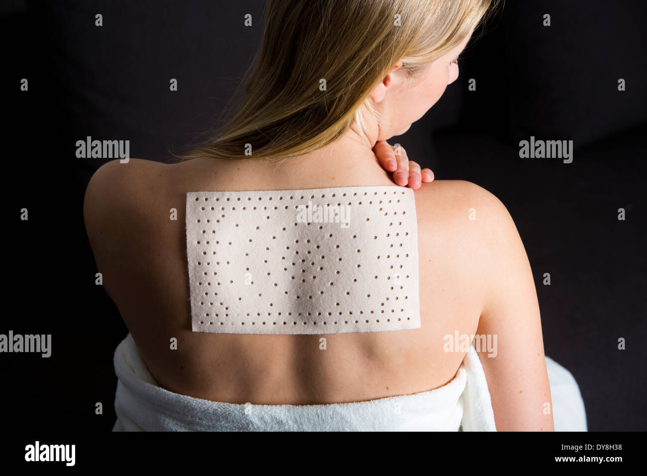 Young woman has back pain, wearing a heat patch Stock Photo