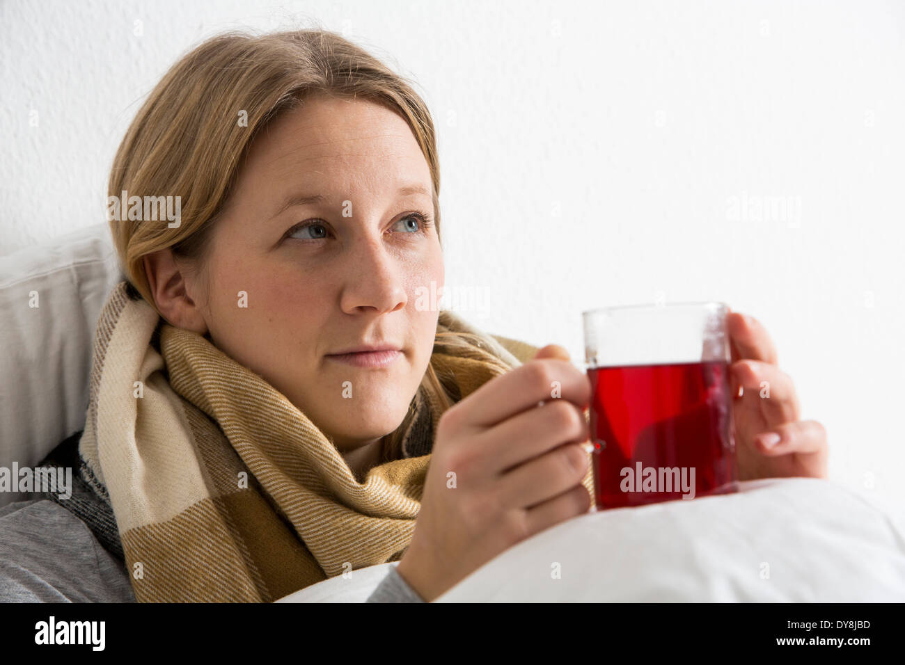 Young woman lying in bed, has a cold, fever, flu, fever, measured with