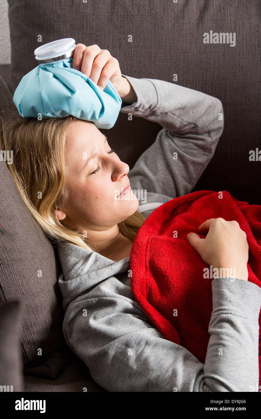 Young woman has a hangover, headache, the head is cooled with an ice