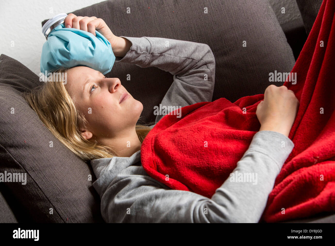 Young woman has a hangover, headache, the head is cooled with an ice