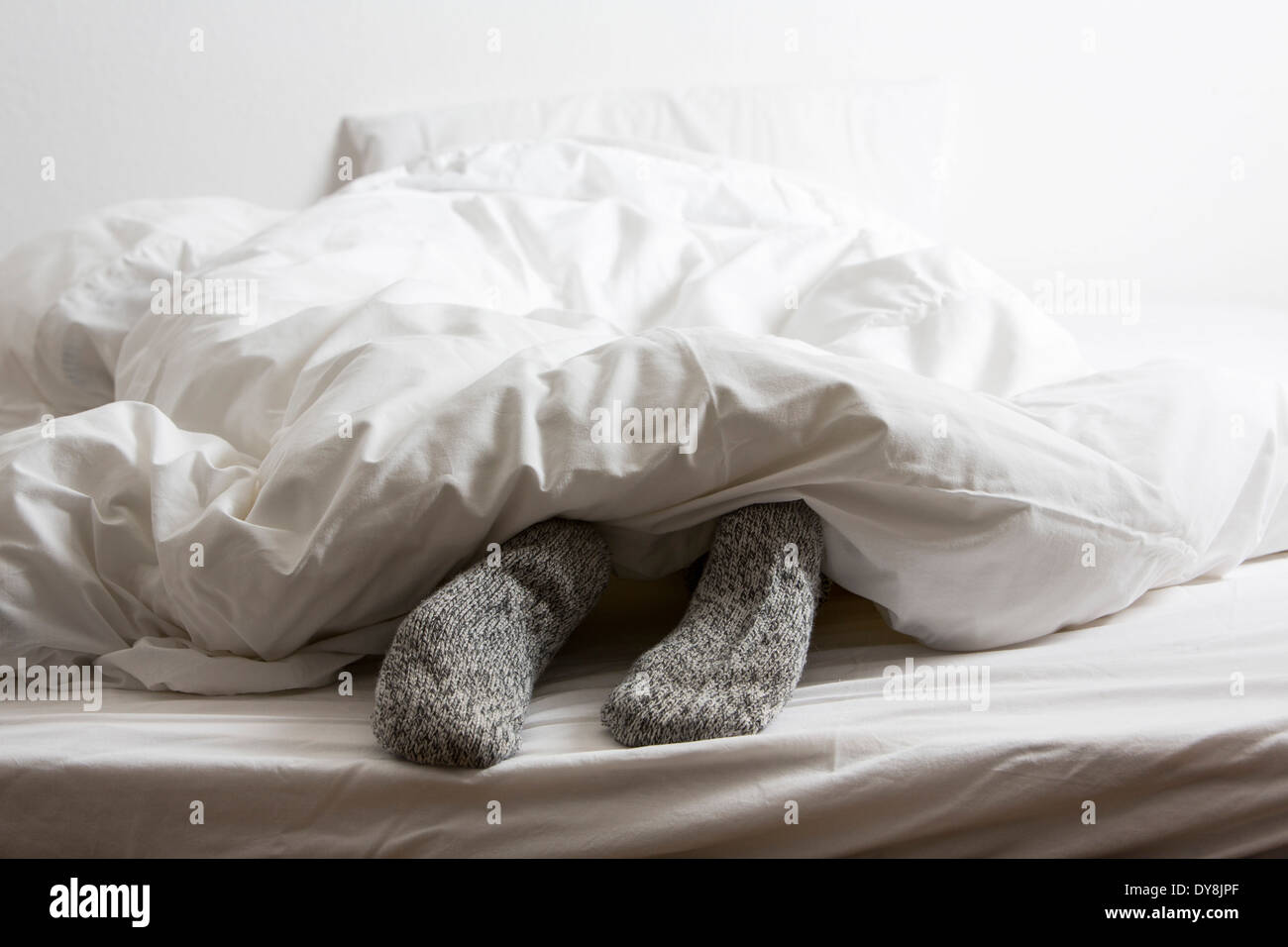 Young woman feels lying in bed, put your feet in warm