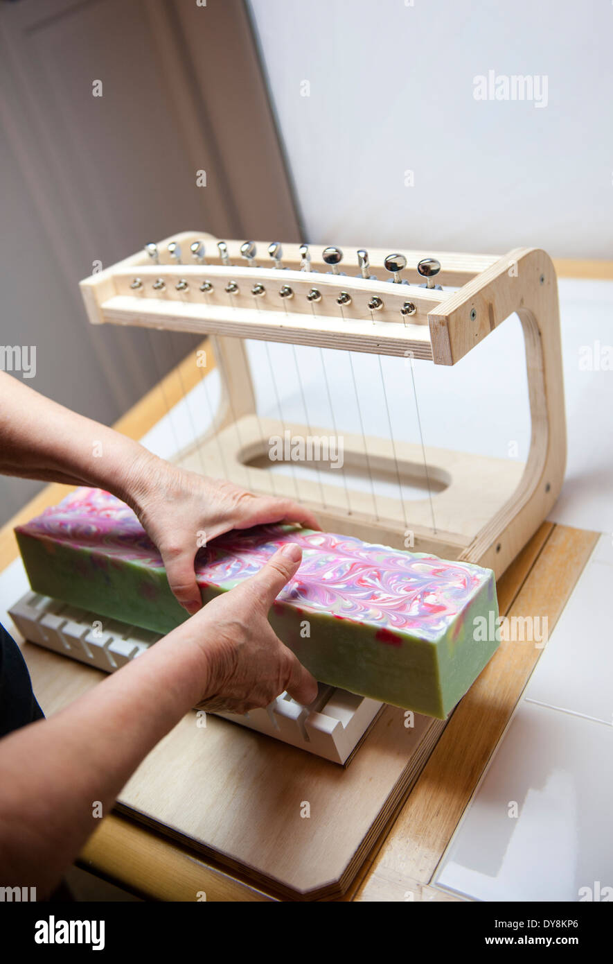 A lady cutting a loaf of soap with a piano wire soap cutter Stock