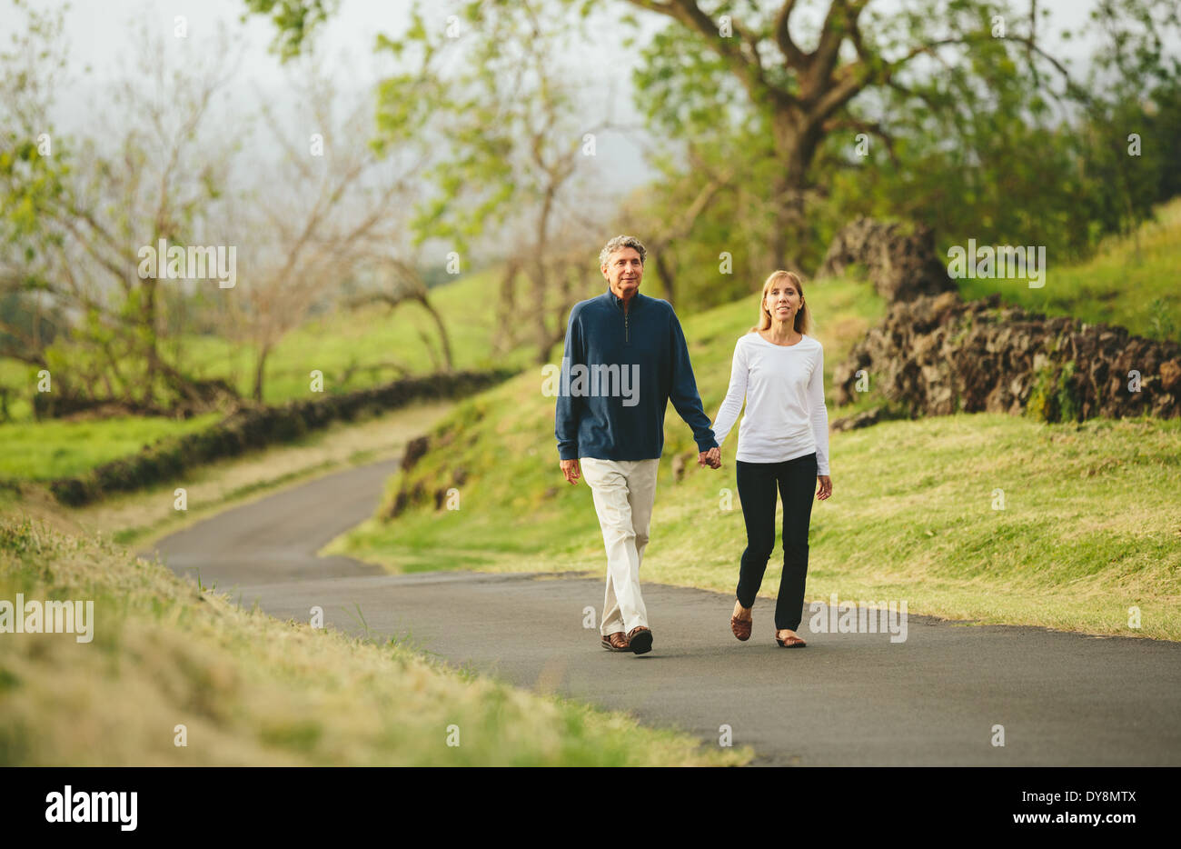 Happy loving middle aged couple walking on beautiful country road Stock Photo