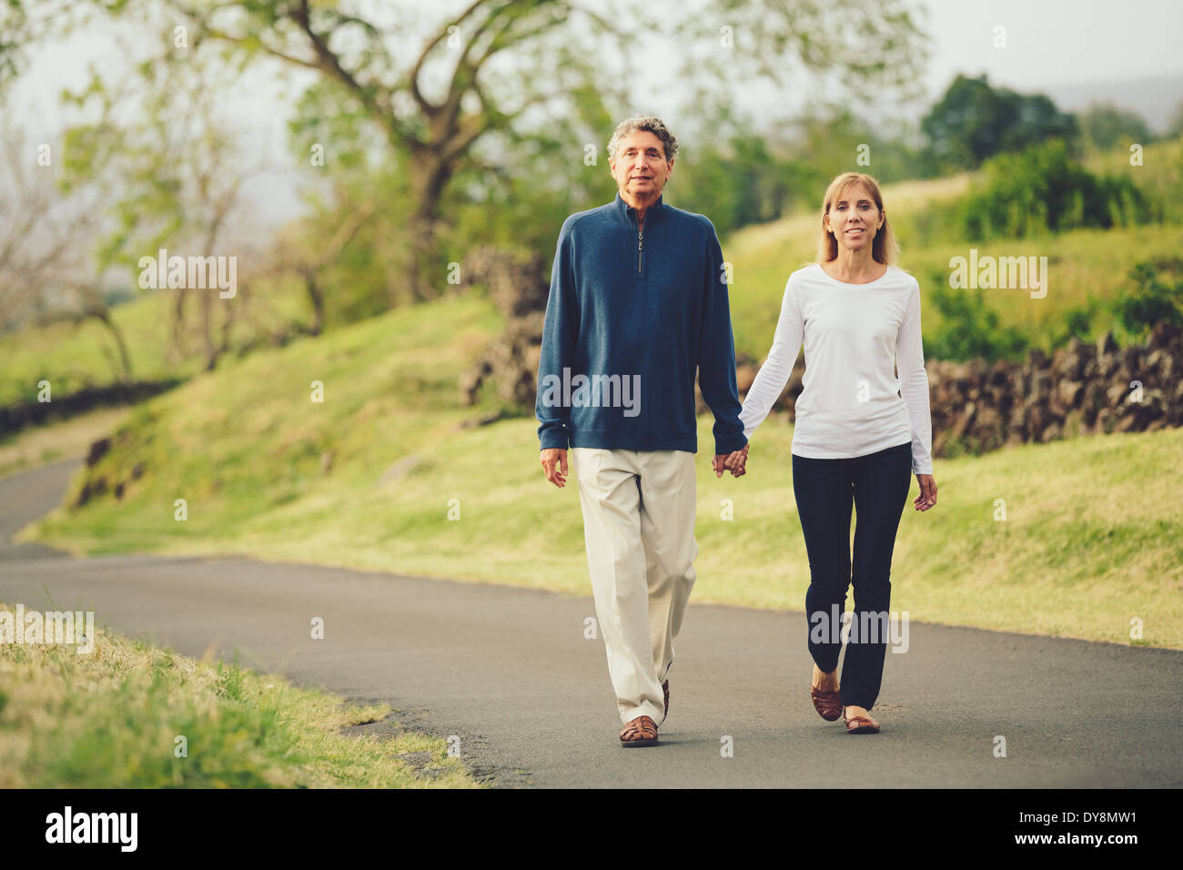 Happy loving middle aged couple walking on beautiful country road Stock Photo