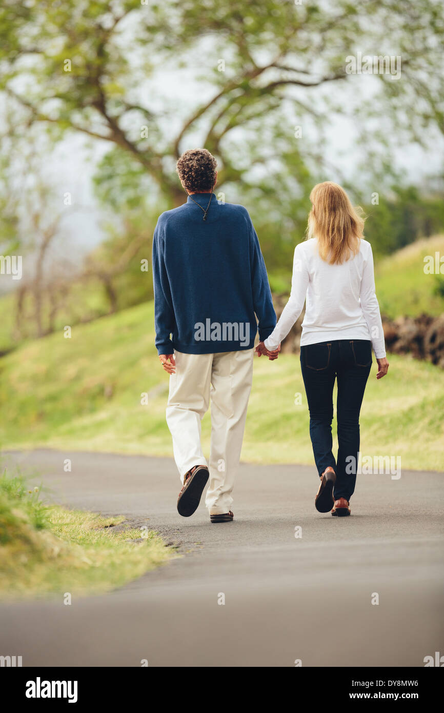 Happy loving middle aged couple walking on beautiful country road Stock Photo