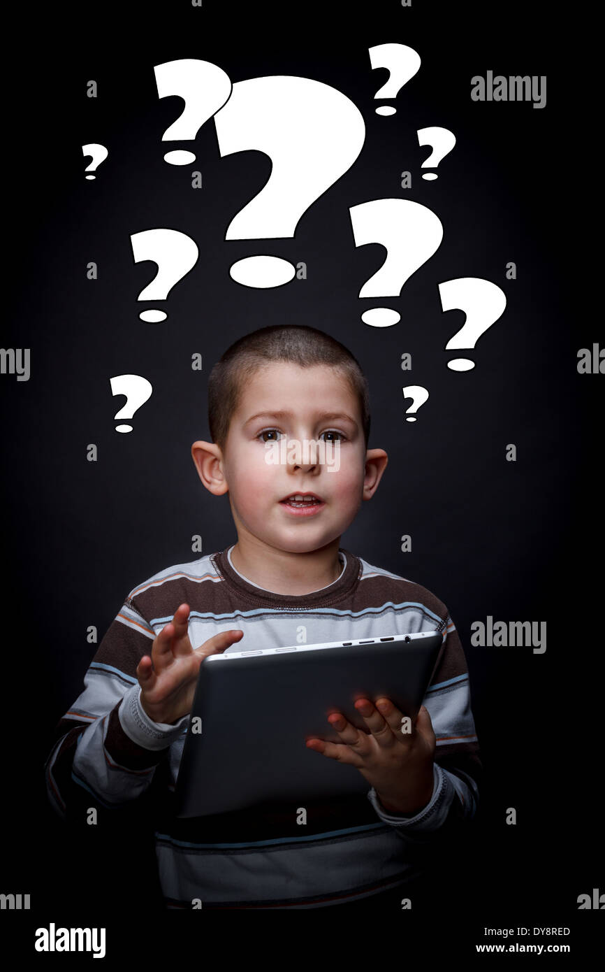 Boy with question mark symbols around his head using tablet Stock Photo