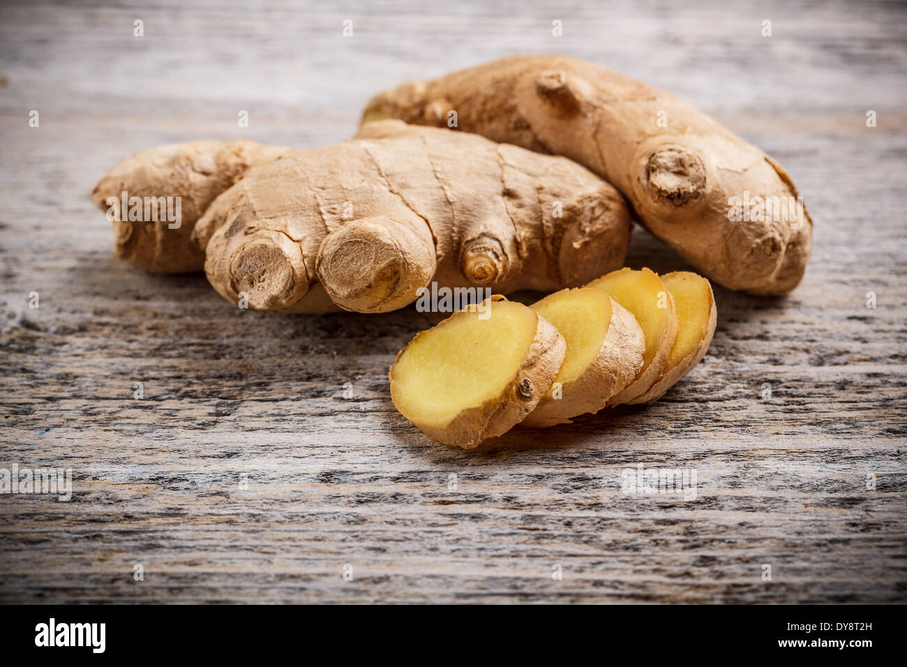 Ginger root sliced on wooden table Stock Photo