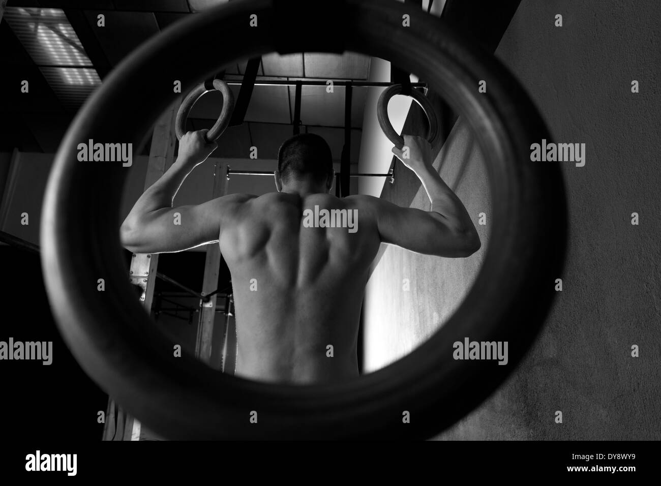 Rings workout man at gym hanging rear back view Stock Photo