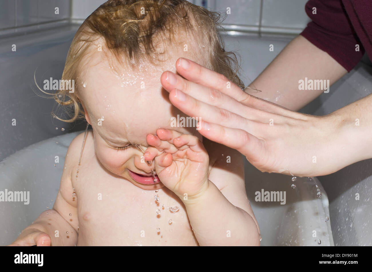 Toddler in bath tub getting washed by mother Stock Photo