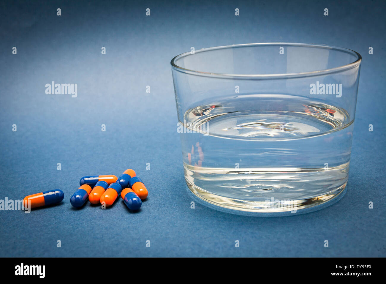 Glass of water and pills isolated on blue Stock Photo