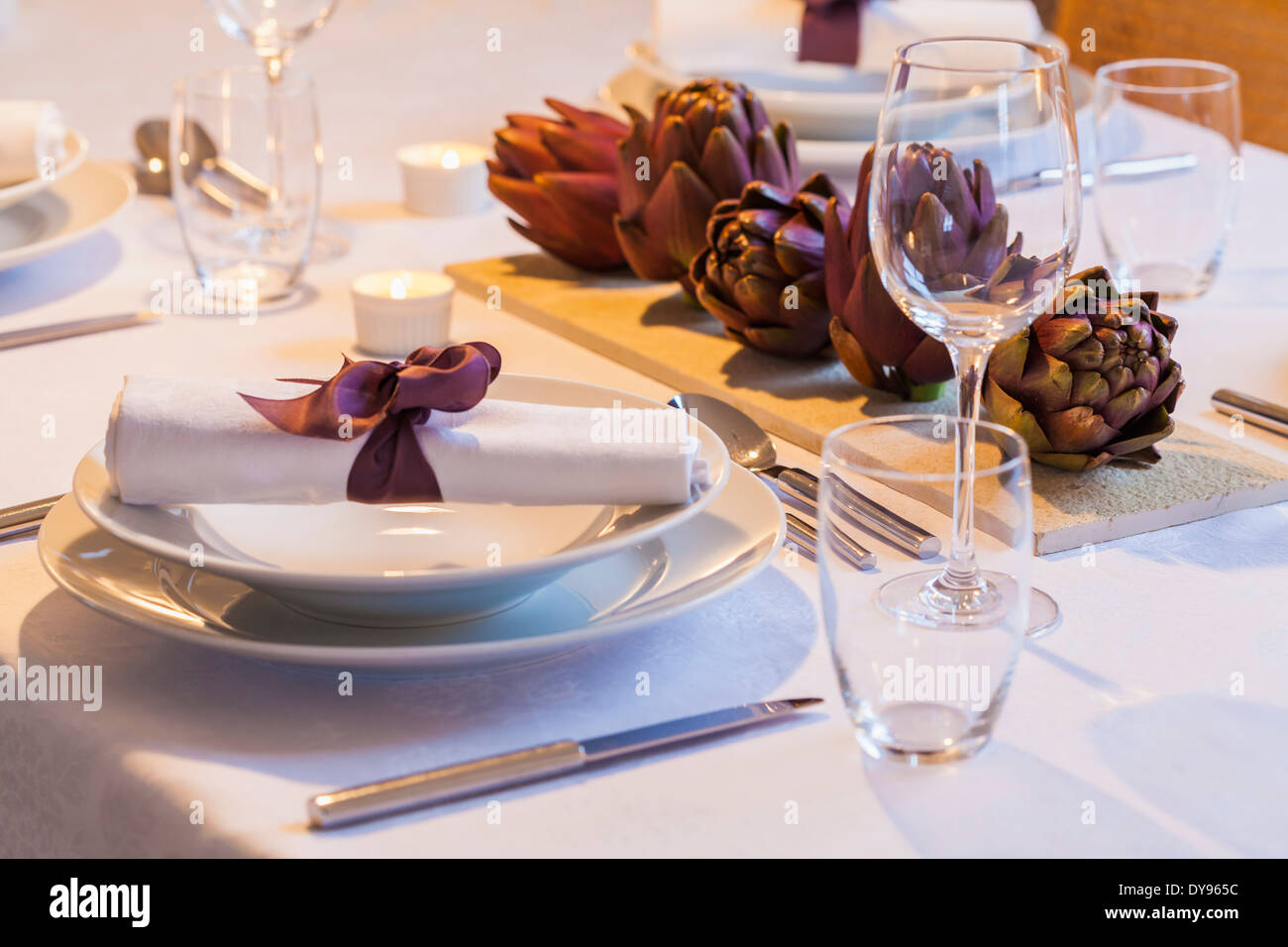 Place setting and decoration with artichokes on festive laid table Stock Photo