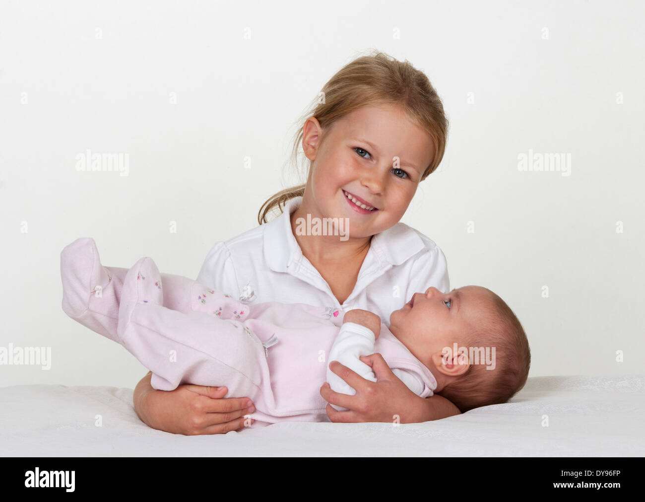 Portrait of smiling little girl holding newborn sister Stock Photo