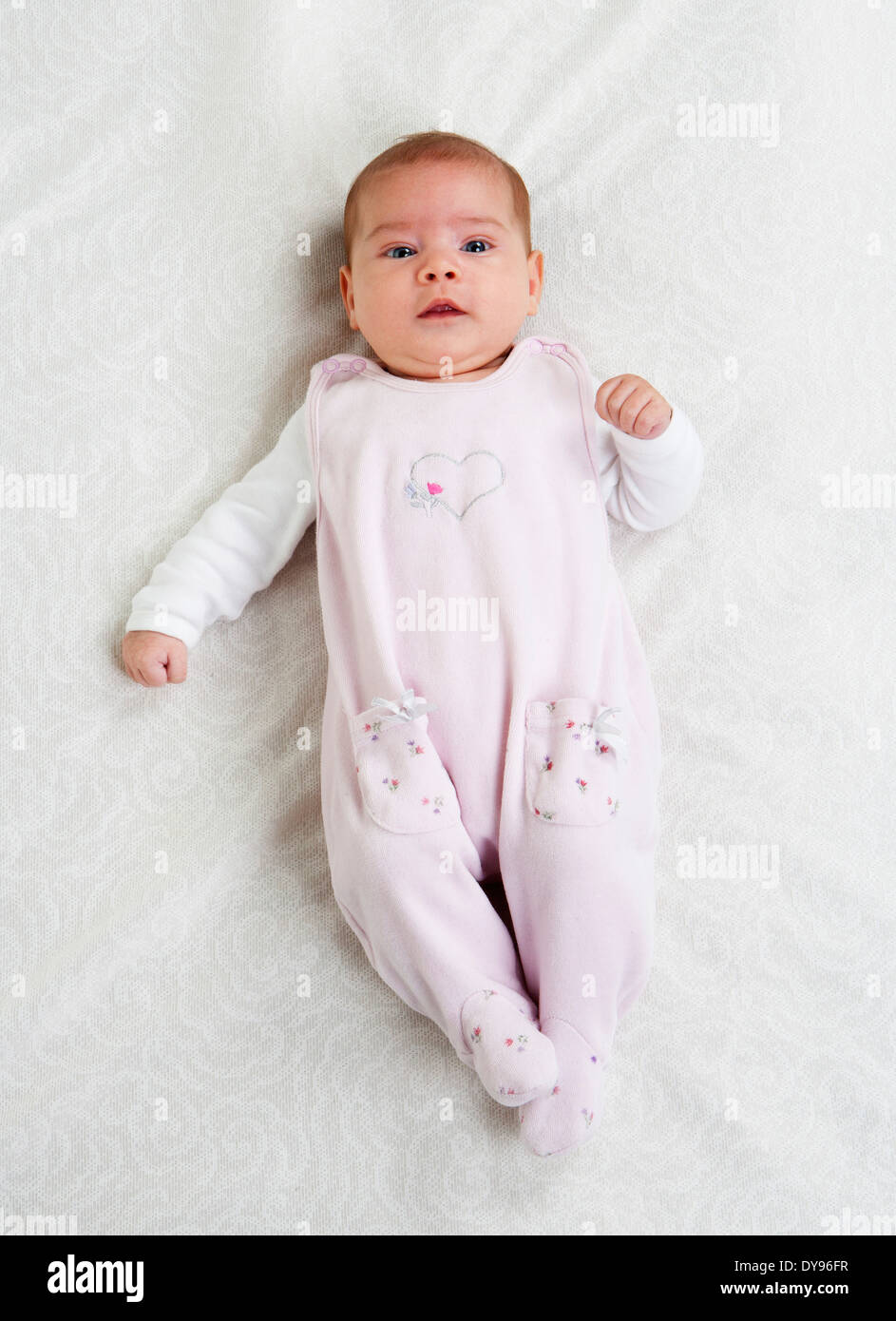 Female baby wearing pink rompers lying on white cloth Stock Photo