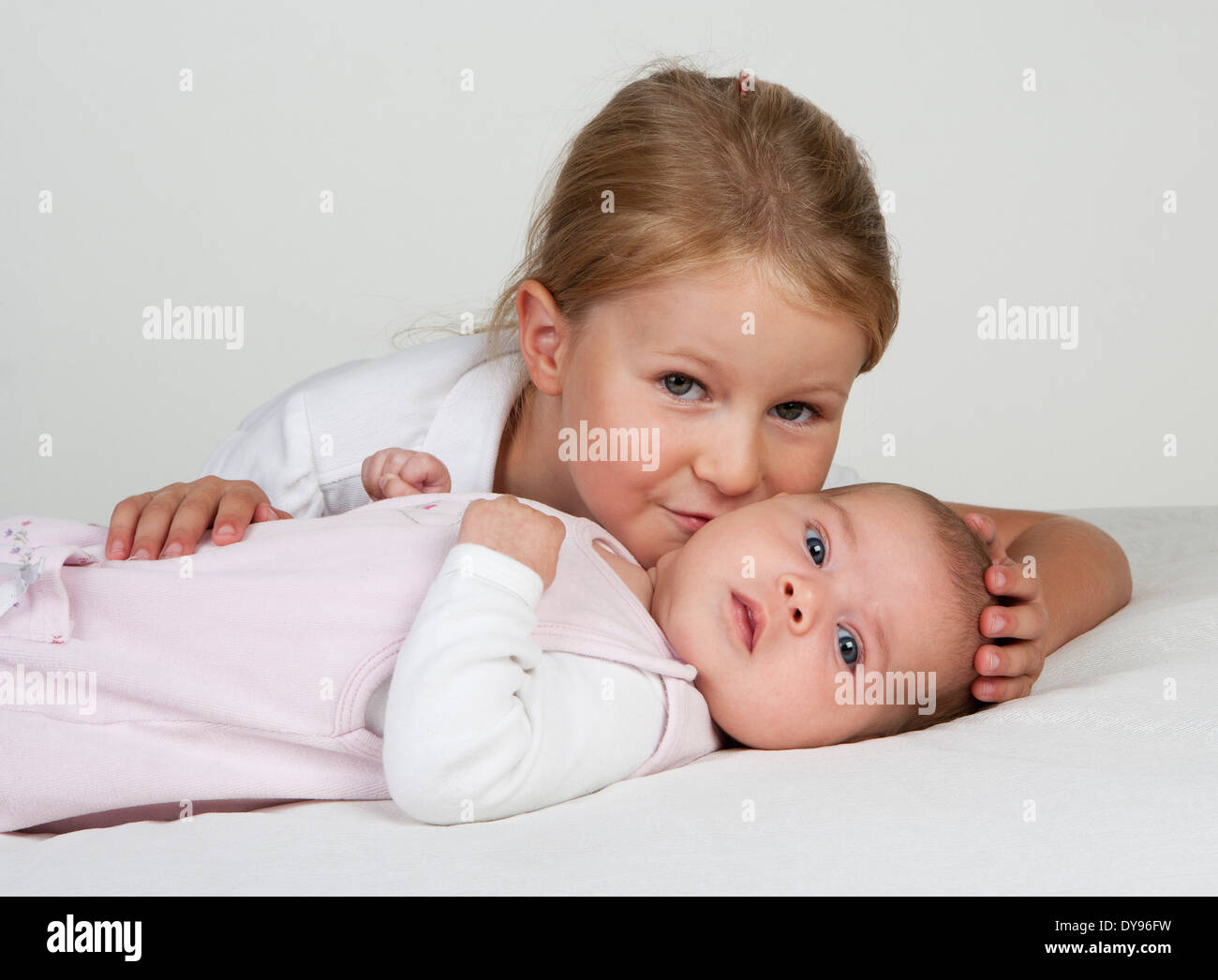 Portrait of little girl kissing newborn sister Stock Photo