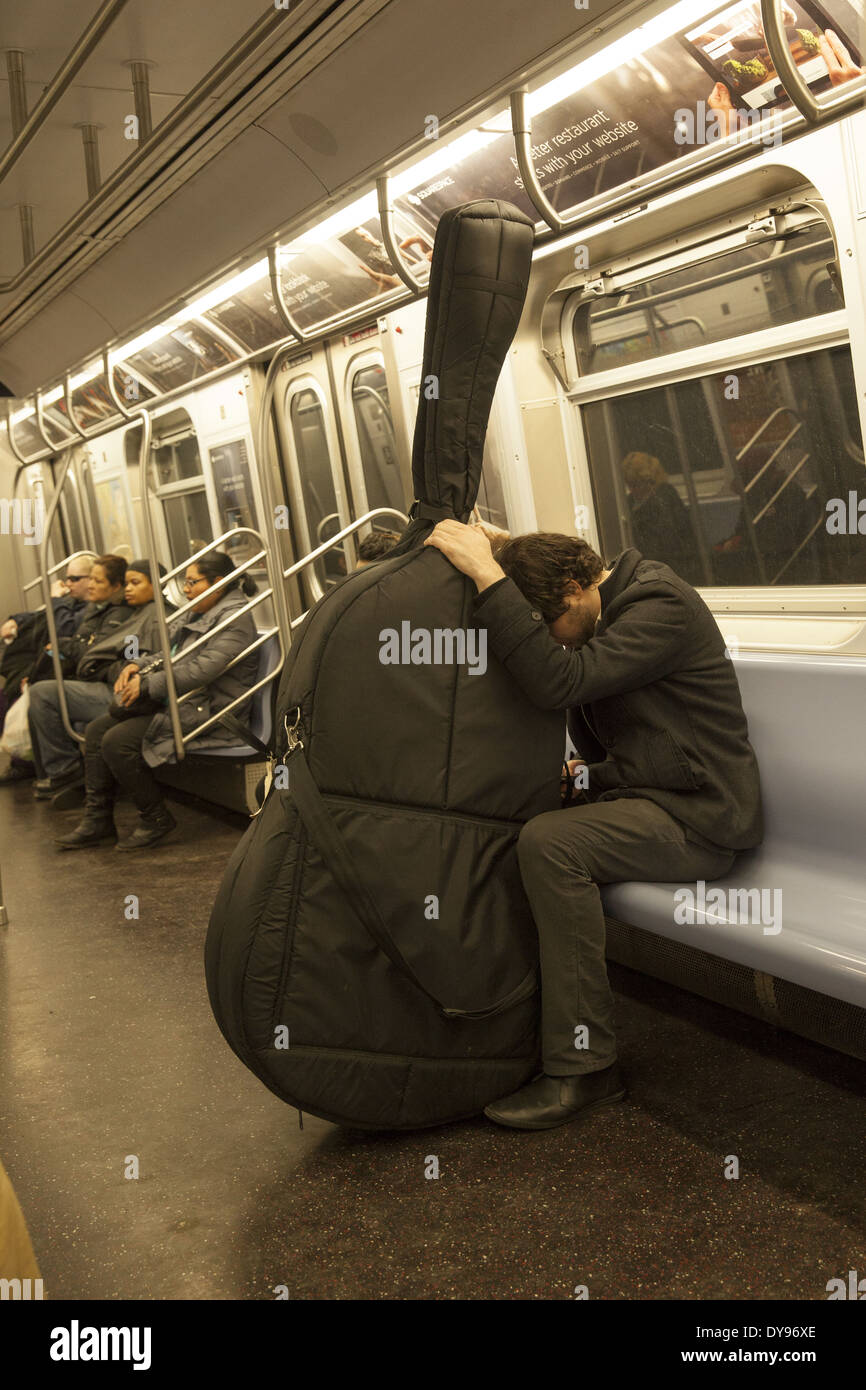 Tired bass player riding the New York City subway in Manhattan. Stock Photo