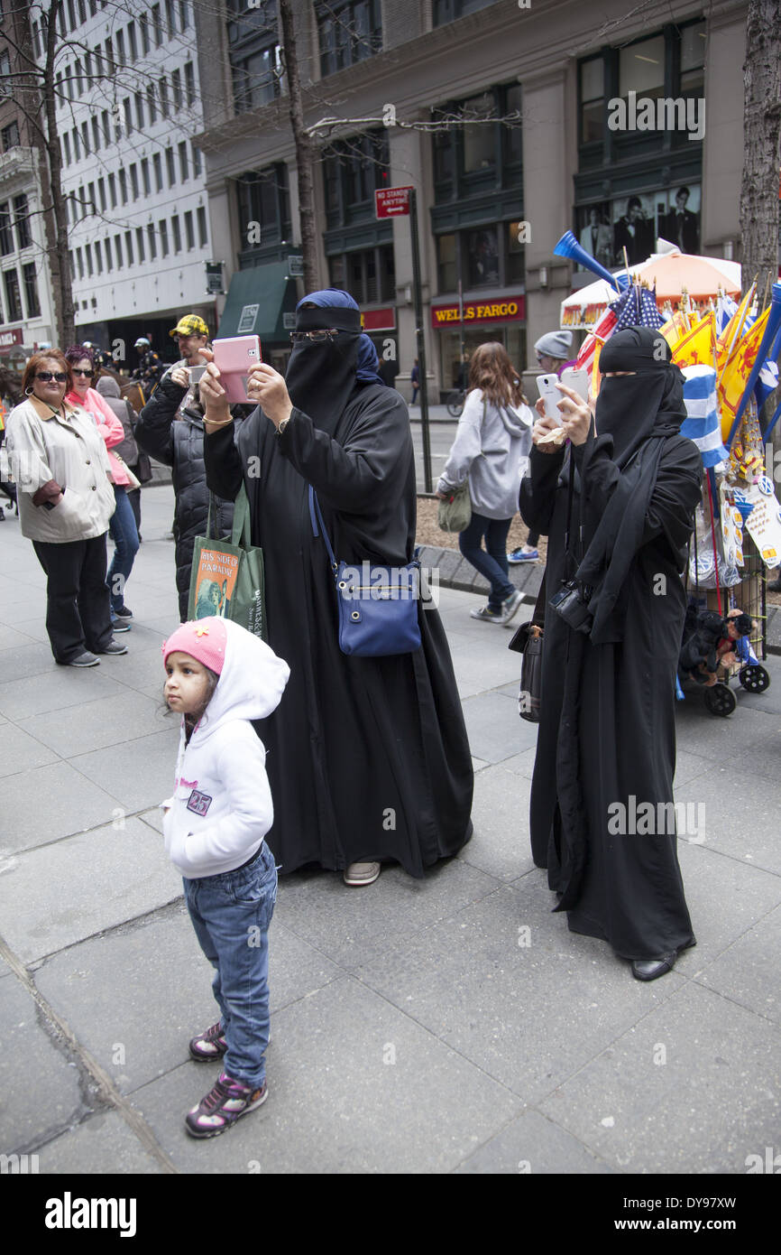 Completely covered Muslim women in Burkas snap photos at the Tartan Day Parade in NYC. Stock Photo