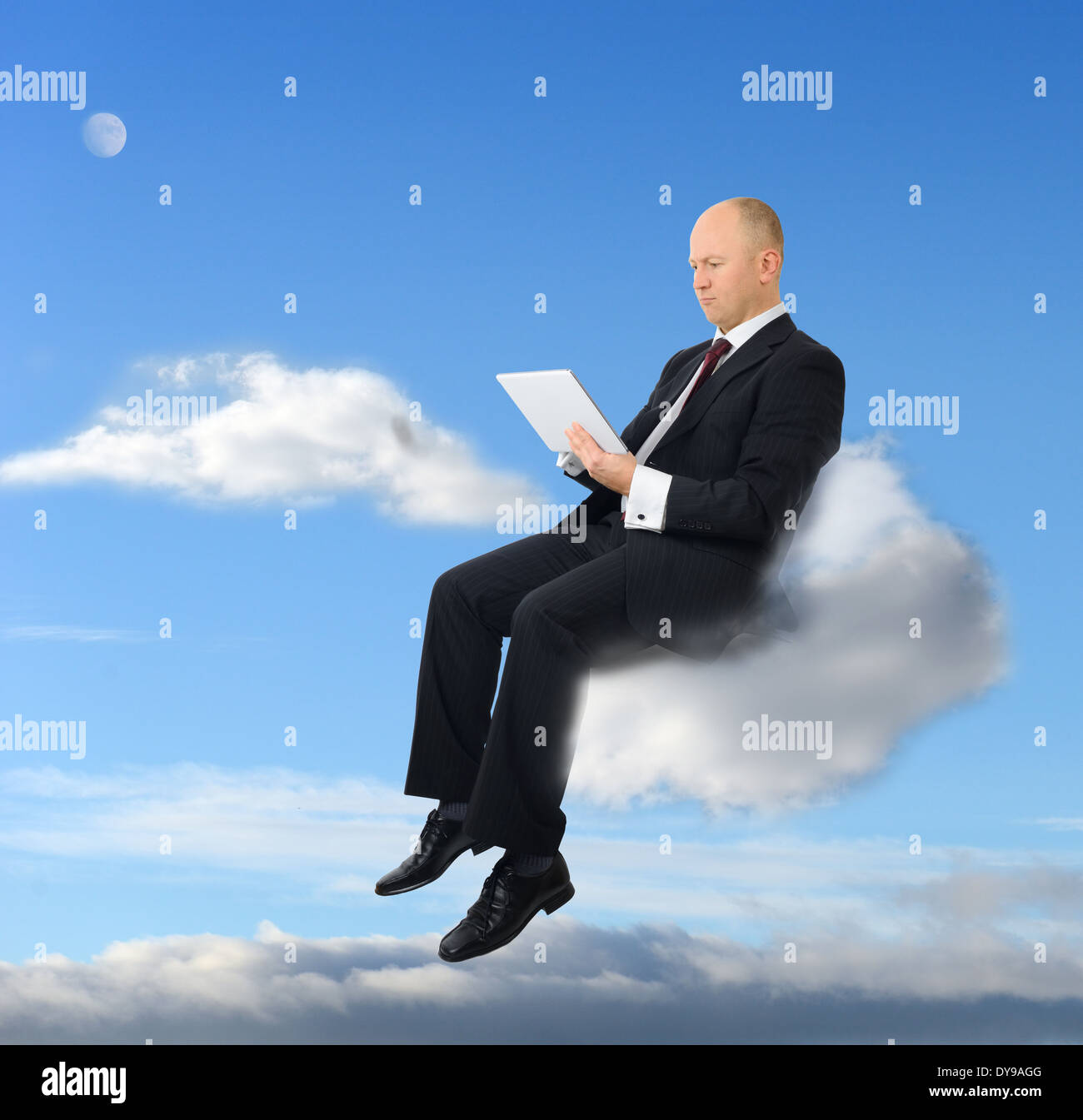 a businessman sitting on a cloud with a tablet pc Stock Photo