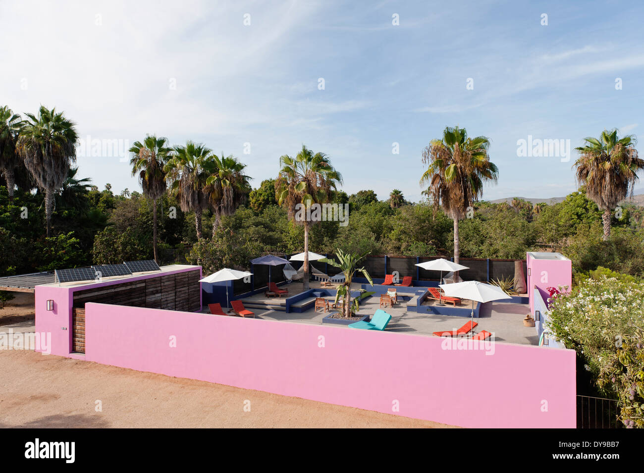 View of hotel courtyard with palm trees, pink outerwall and solar panels Stock Photo