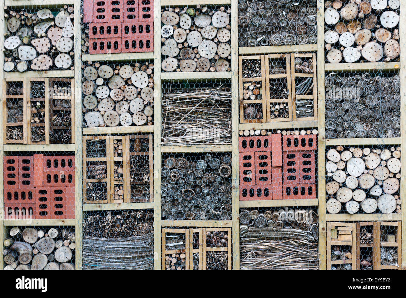 Sections of a bug hotel made from drilled wood, bricks, straw, twigs and pine cones. Stock Photo