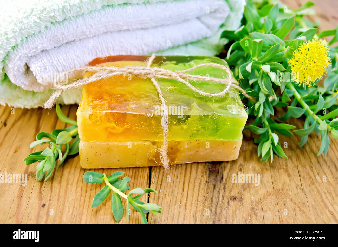 Two pieces of homemade soap, tied with twine with Rhodiola rosea flowers on a background of wooden boards Stock Photo