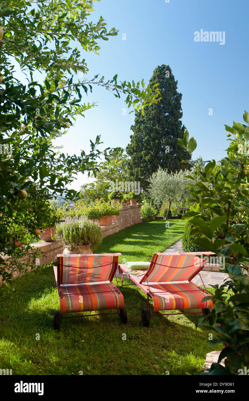 Pair of striped sunloungers in Umbrian garden rich with plants and trees Stock Photo