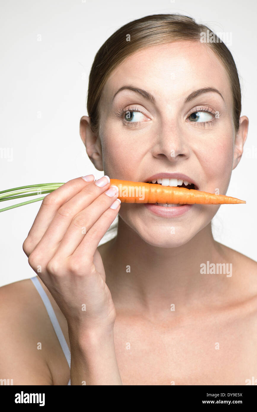 Young woman biting into carrot Stock Photo