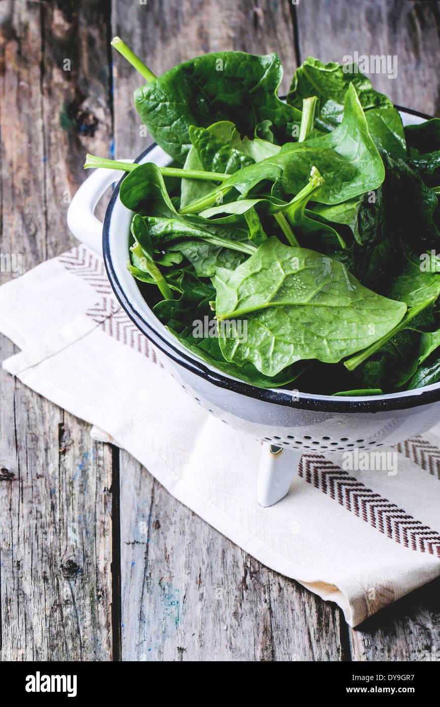 Fresh spinach in metal colander over wooden background Stock Photo