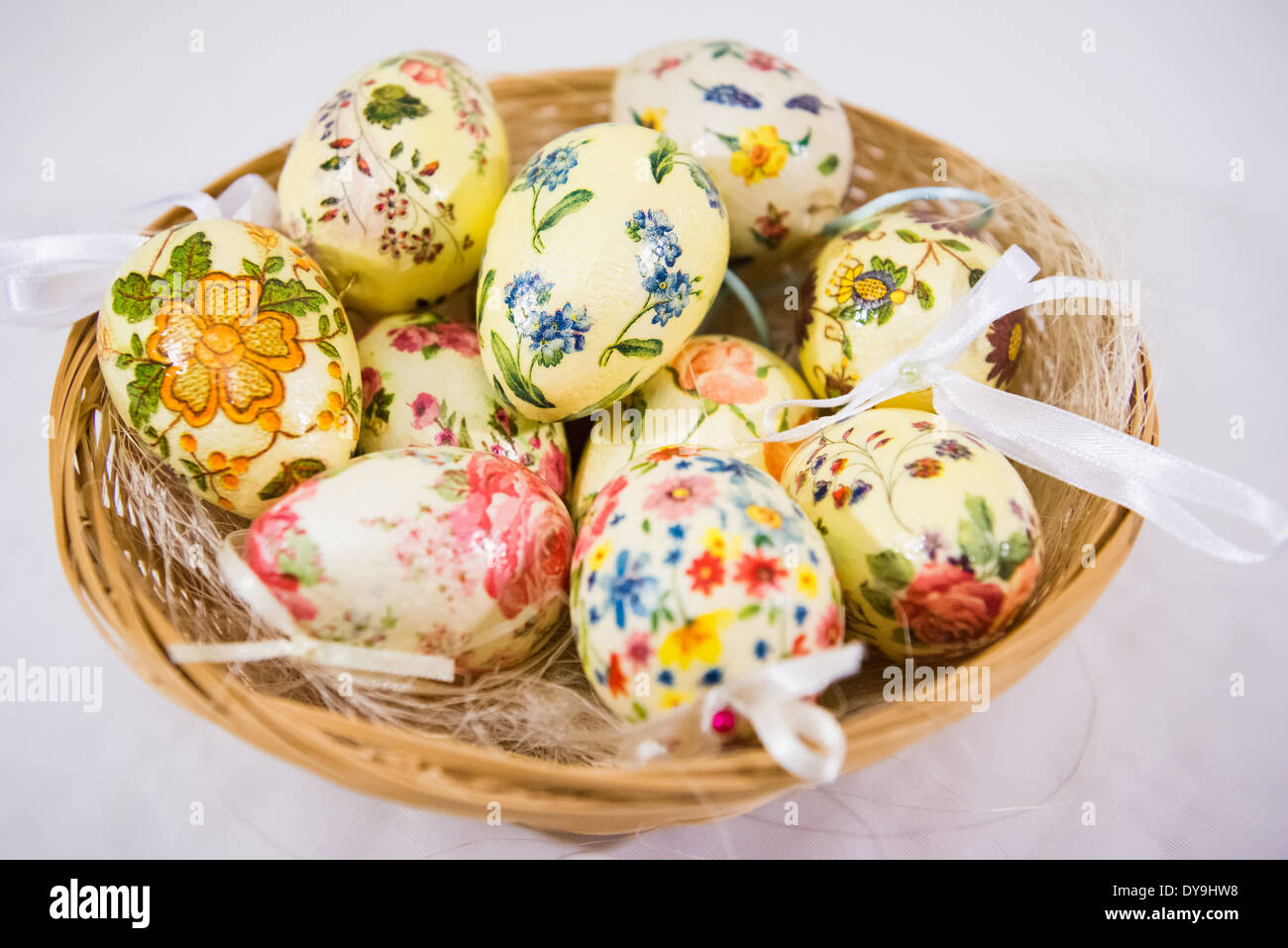 Group of colorful easter eggs decorated with flowers made by decoupage technique, in a basket on light background Stock Photo