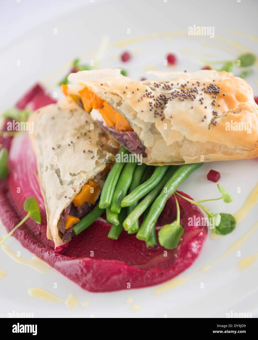 Red onion and squash filo pastry parcel , served with green beans and beetroot purée. Stock Photo