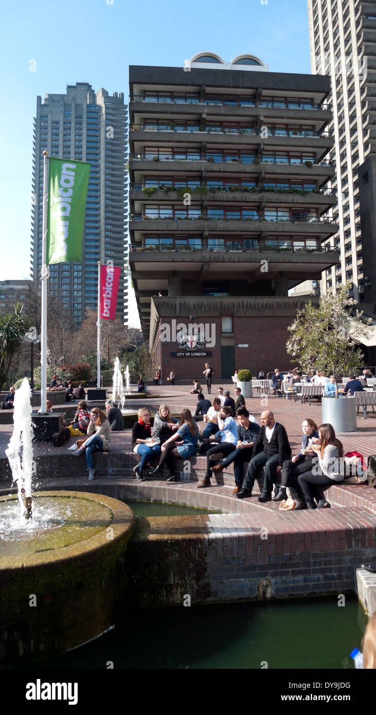 People sitting by the fountain in the sunshine outside the Barbican Centre London England UK KATHY DEWITT Stock Photo